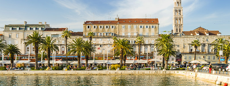 Till sjöss och vy över vacker husfasad och palmer längs ett promenadstråk i Split på kryssning i den kroatiska skärgåden.